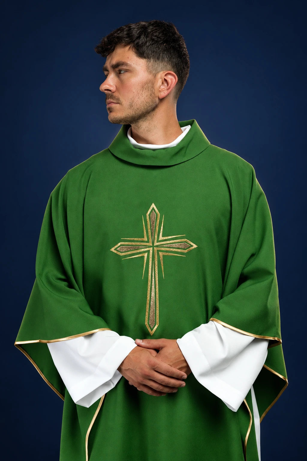 Front view of a green chasuble with a gold embroidered cross and gold-trimmed sleeves over a white alb