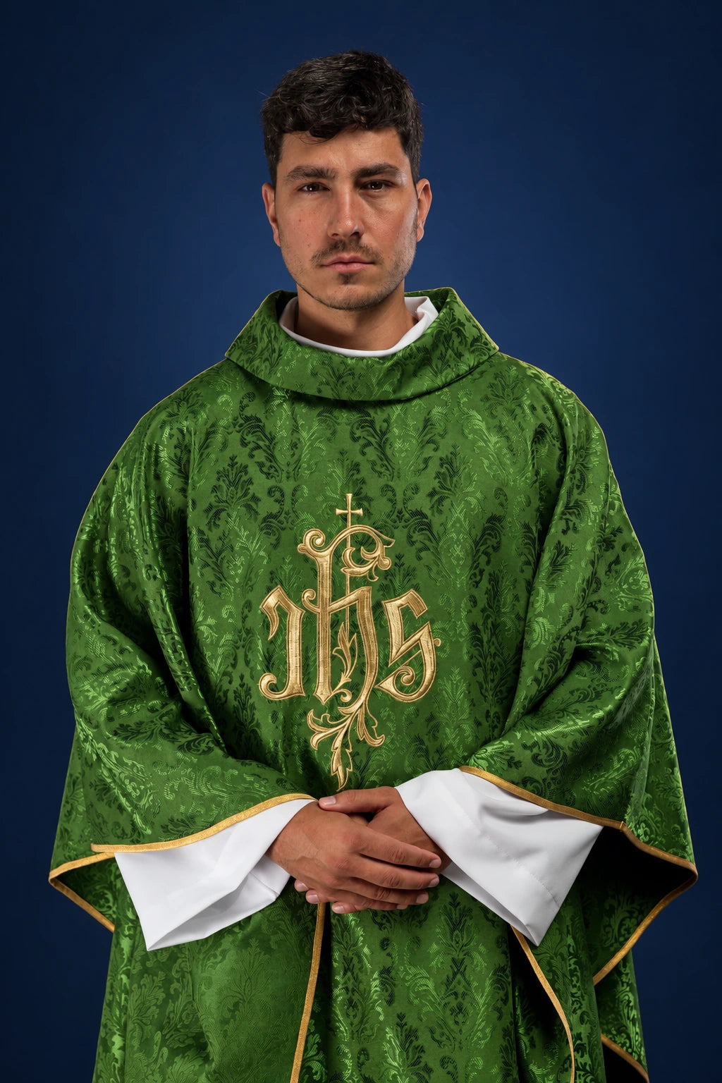 Front view of a green chasuble with gold embroidered IHS motif and gold trim over white sleeves