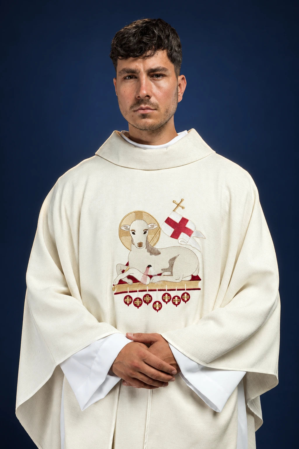 Front view of an ivory chasuble with an embroidered lamb and red cross motif on the chest
