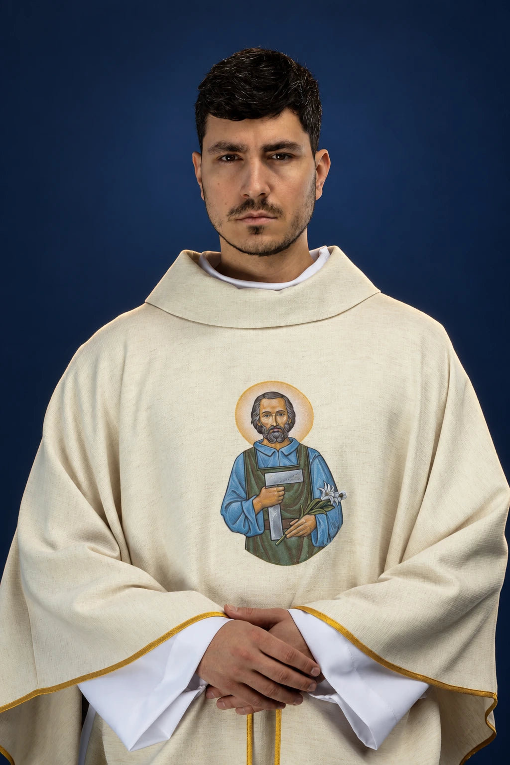 Front view of an ivory chasuble with gold trim and a central Saint Joseph the Worker embroidered medallion