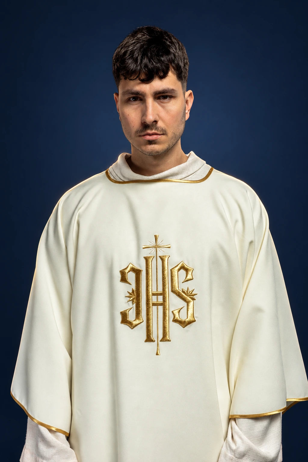 Front view of an ivory dalmatic with gold trim and large gold IHS embroidery on the chest