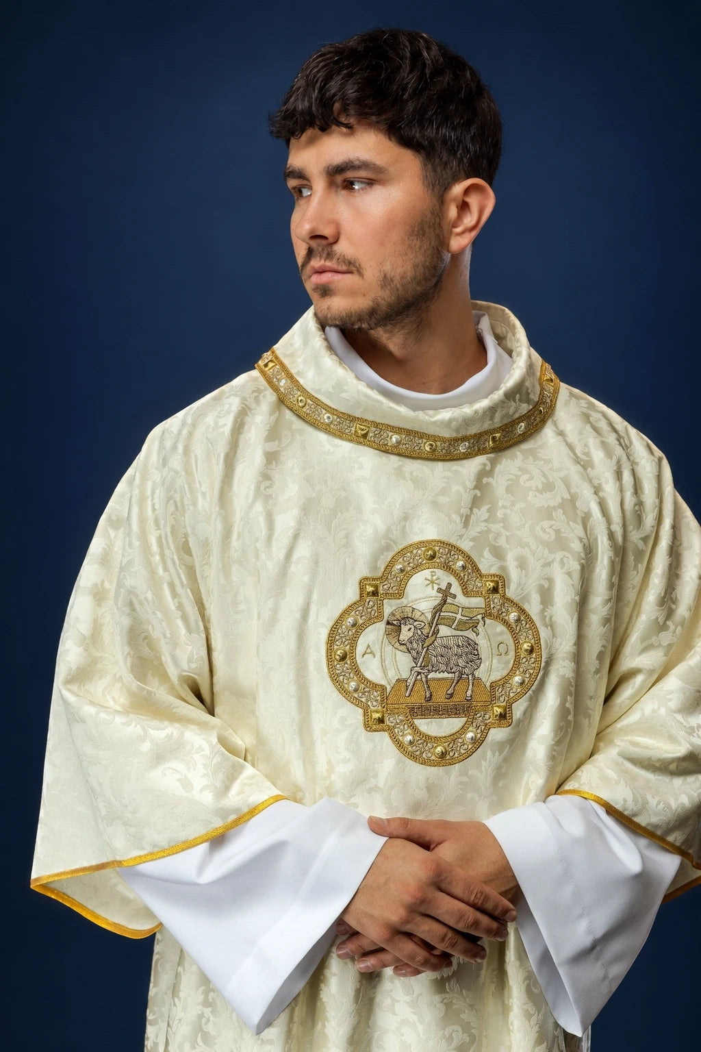 Front view of an ivory dalmatic with gold trim and Paschal Lamb emblem on the chest.
