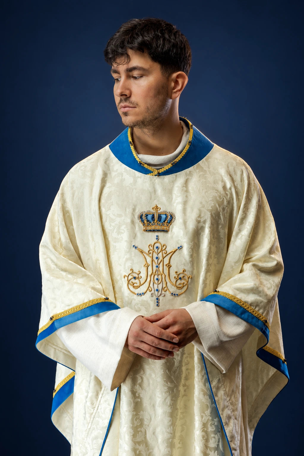 Front view of ivory Marian chasuble with blue trim and jeweled crown and M monogram embroidery