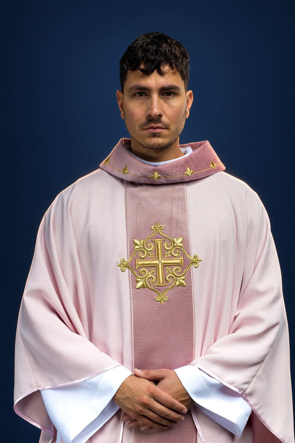 Front view of a pale pink chasuble with a gold embroidered cross and matching collar trim