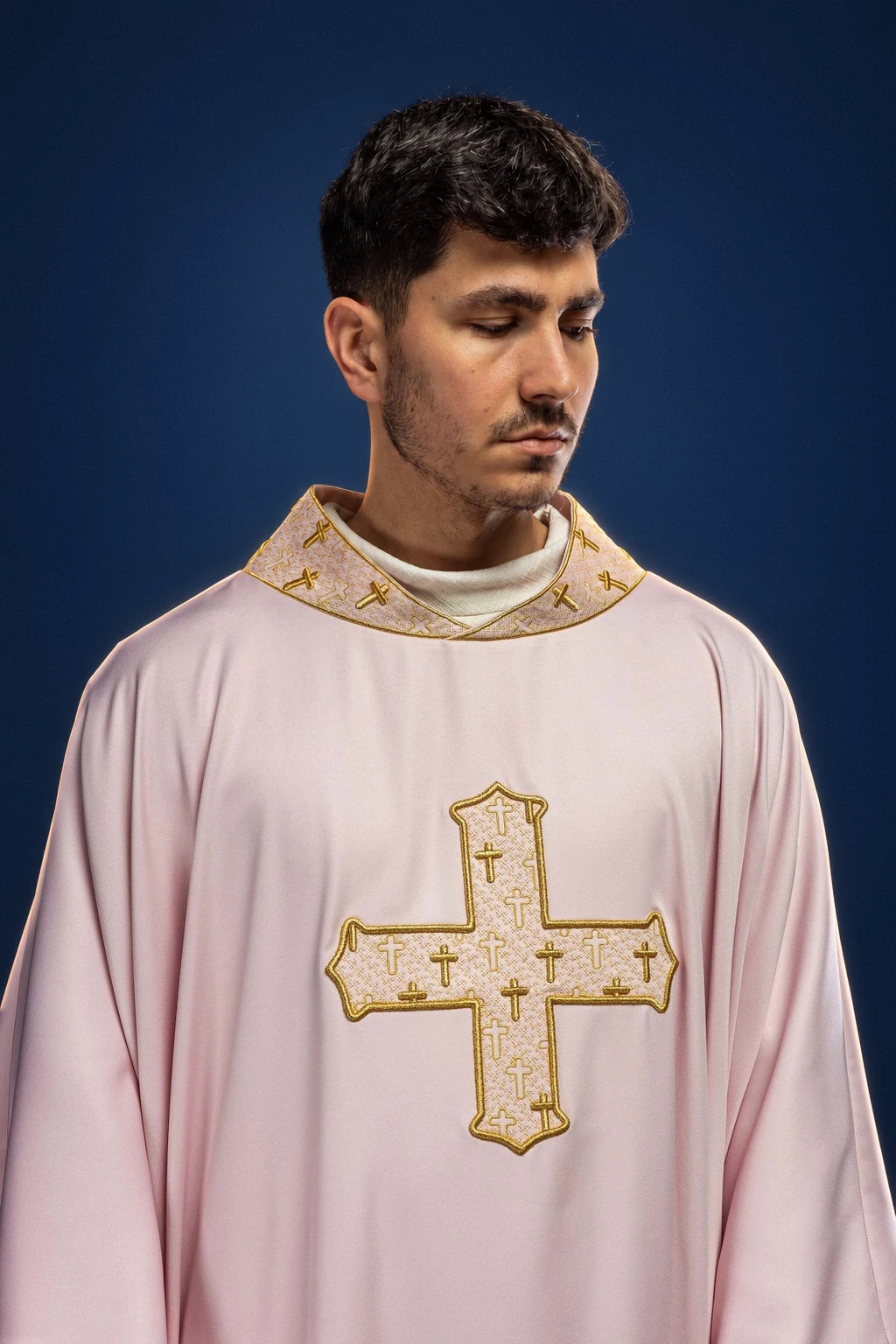 Front view of a pale rose chasuble with a gold-embroidered cross and matching cross-patterned collar trim