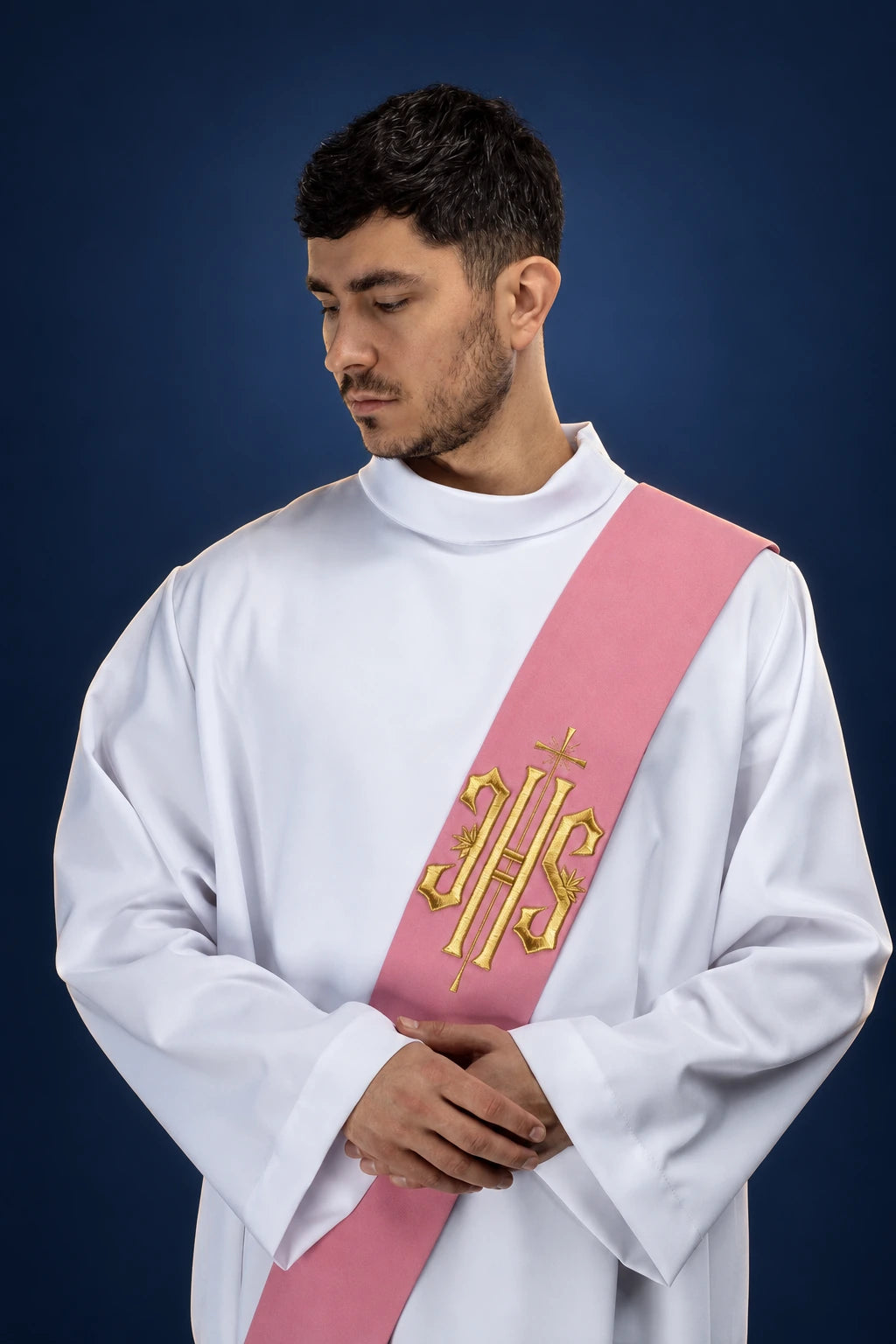 Front view of a pink deacon stole with gold IHS cross embroidery, worn over a white alb