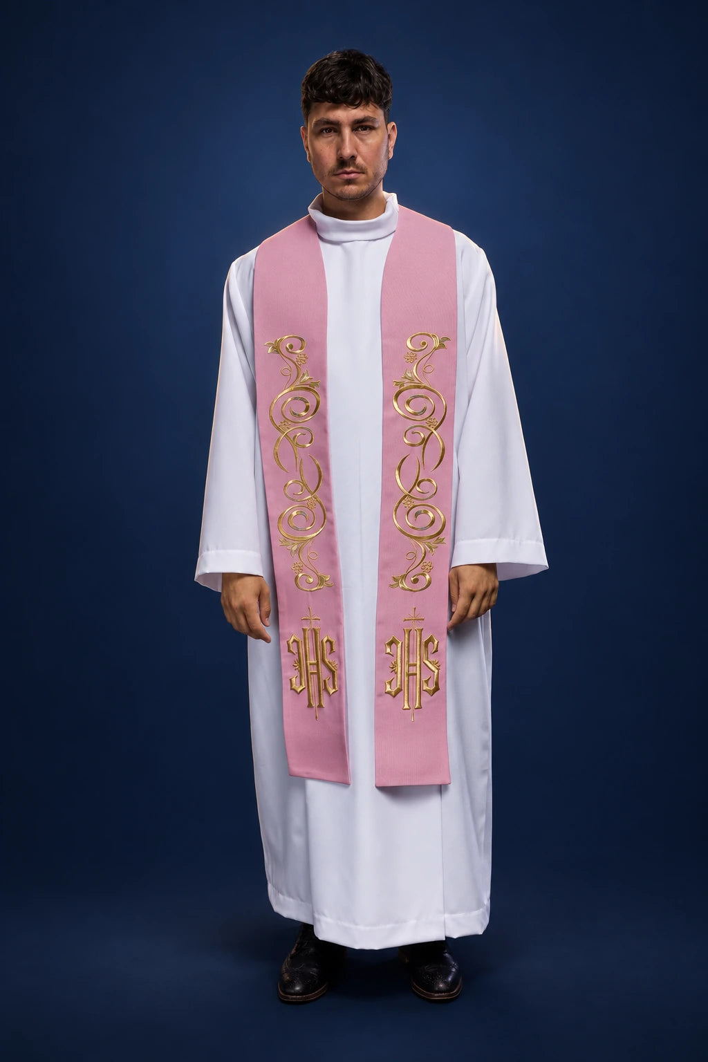 Front view of a pink priest stole with gold floral embroidery and IHS monograms, worn over a white alb