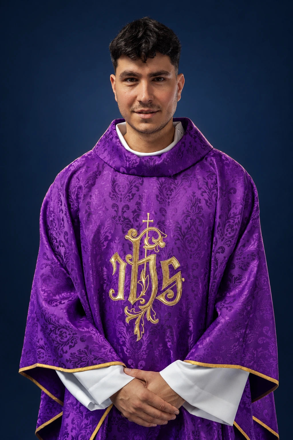 Front view of purple chasuble with gold embroidered IHS motif and gold trim, worn over white sleeves