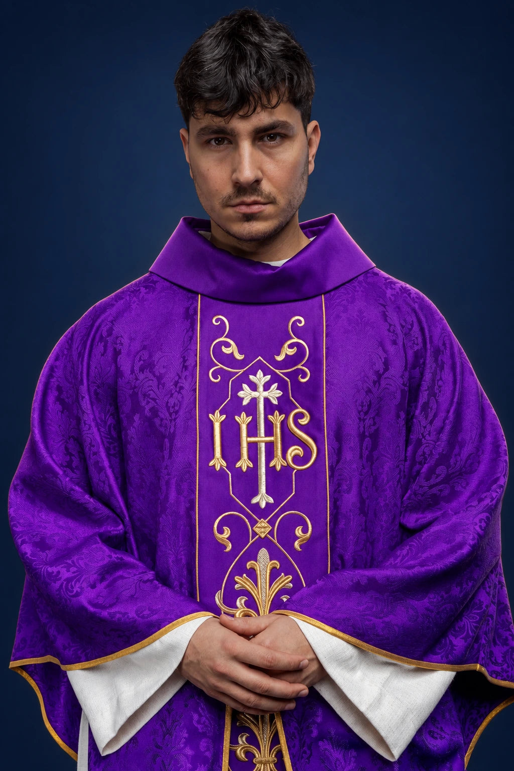 Front view of a purple chasuble with gold IHS embroidery and decorative patterned panels.