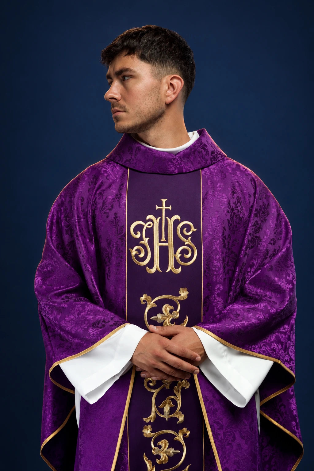 Front view of a purple chasuble with gold IHS orphrey and embroidered scrollwork on the front panel