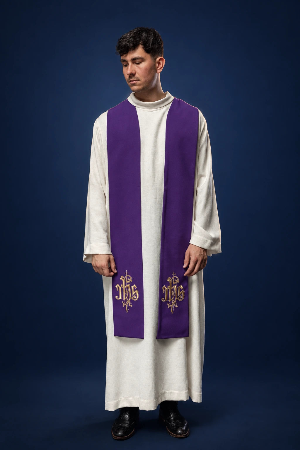 Front view of a purple stole with embroidered IHS motifs, worn over a white alb.