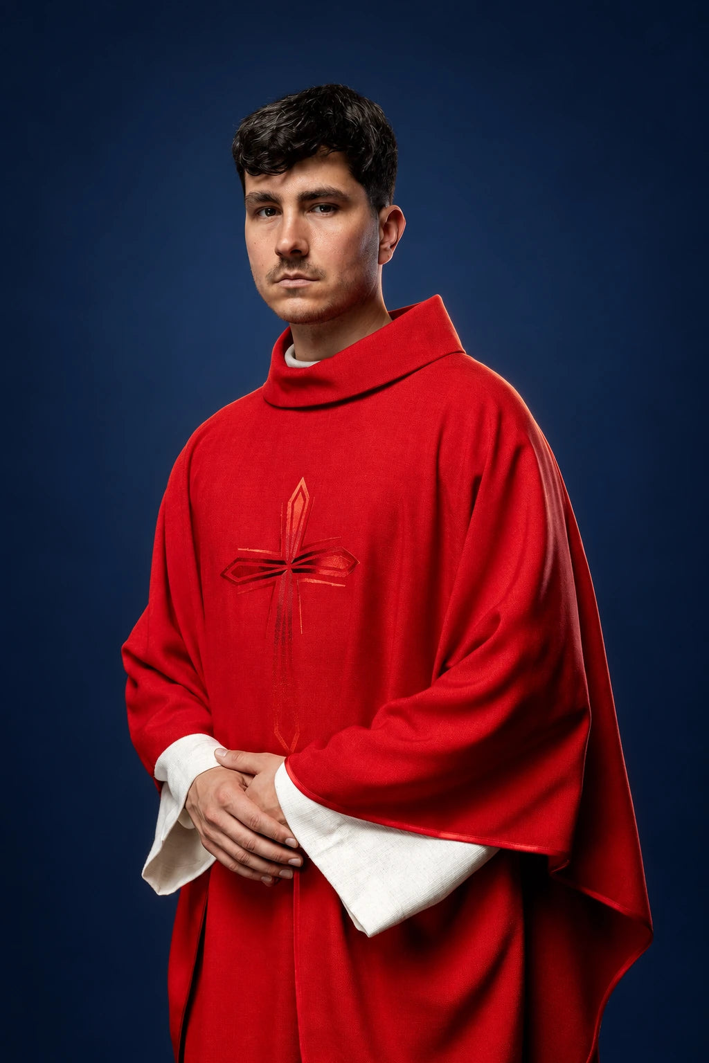 Front view of a red chasuble with a central embroidered cross and white under-sleeves showing