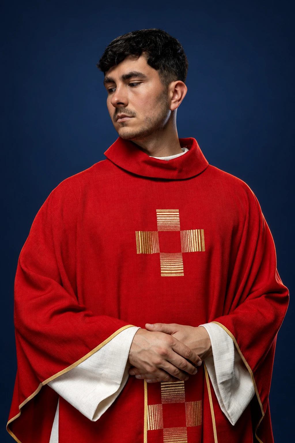 Front view of a red chasuble with gold-embroidered cross on the chest and white trim at the sleeves