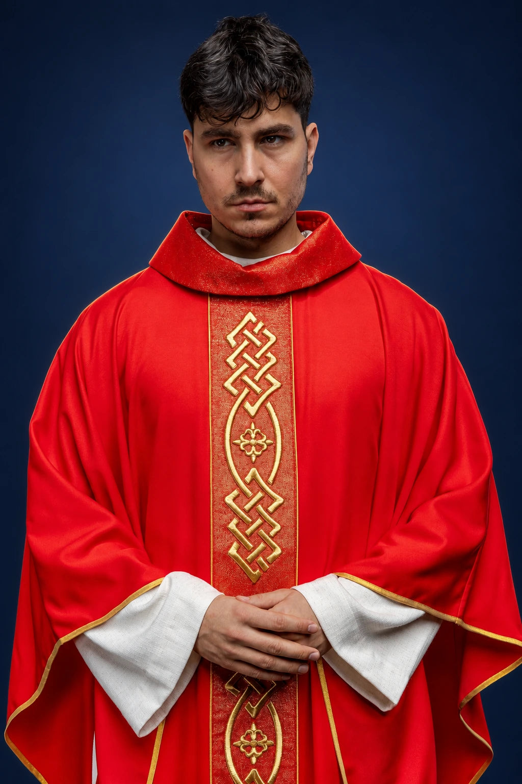 Front view of a red chasuble with gold embroidery and cross motif, worn over white sleeves