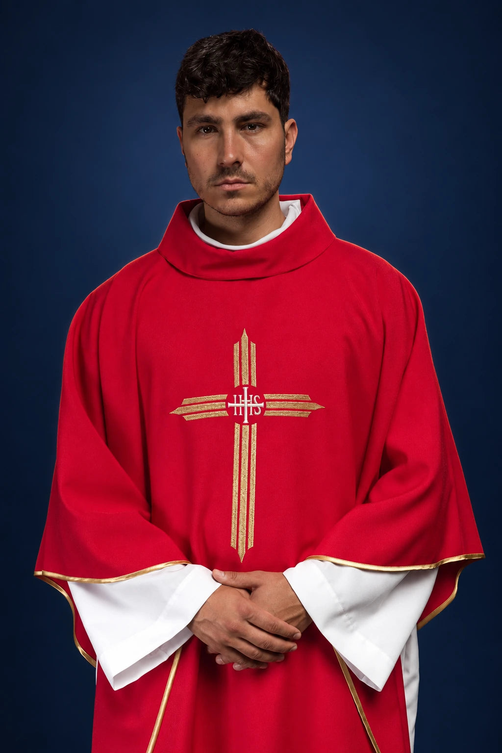 Front view of a red chasuble with gold IHS cross embroidery and white under-sleeves visible