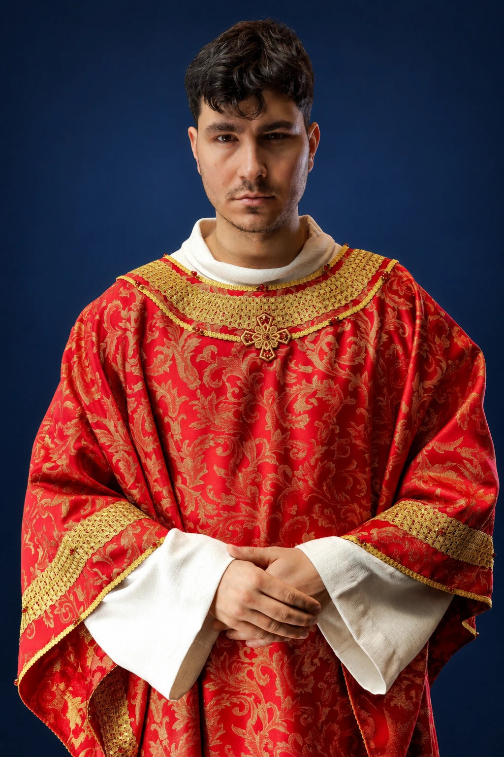 Front view of a red chasuble with gold trim and floral brocade, worn over a white alb