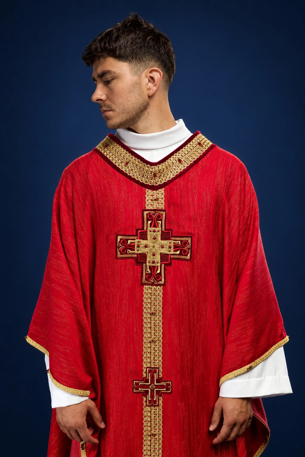 Front view of a red chasuble with gold trim and a vertical embroidered cross design with stones