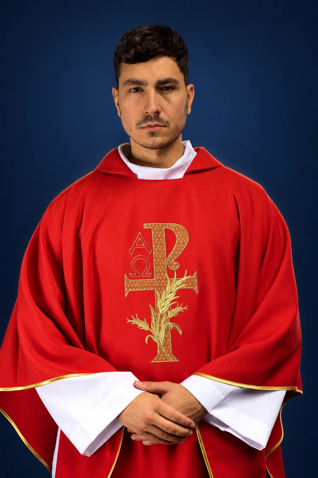 Front view of a red chasuble with wide collar and gold Alpha Omega embroidery at center.