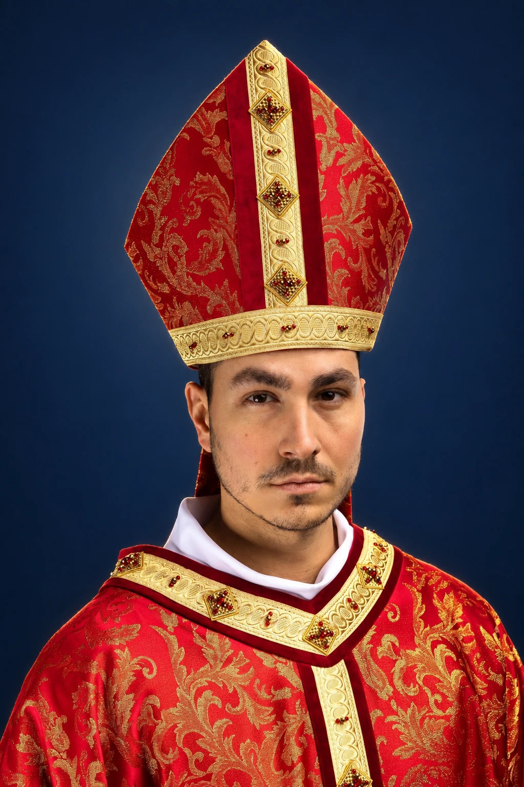 Front view of a red and gold miter with jeweled vertical bands and matching vestment trim