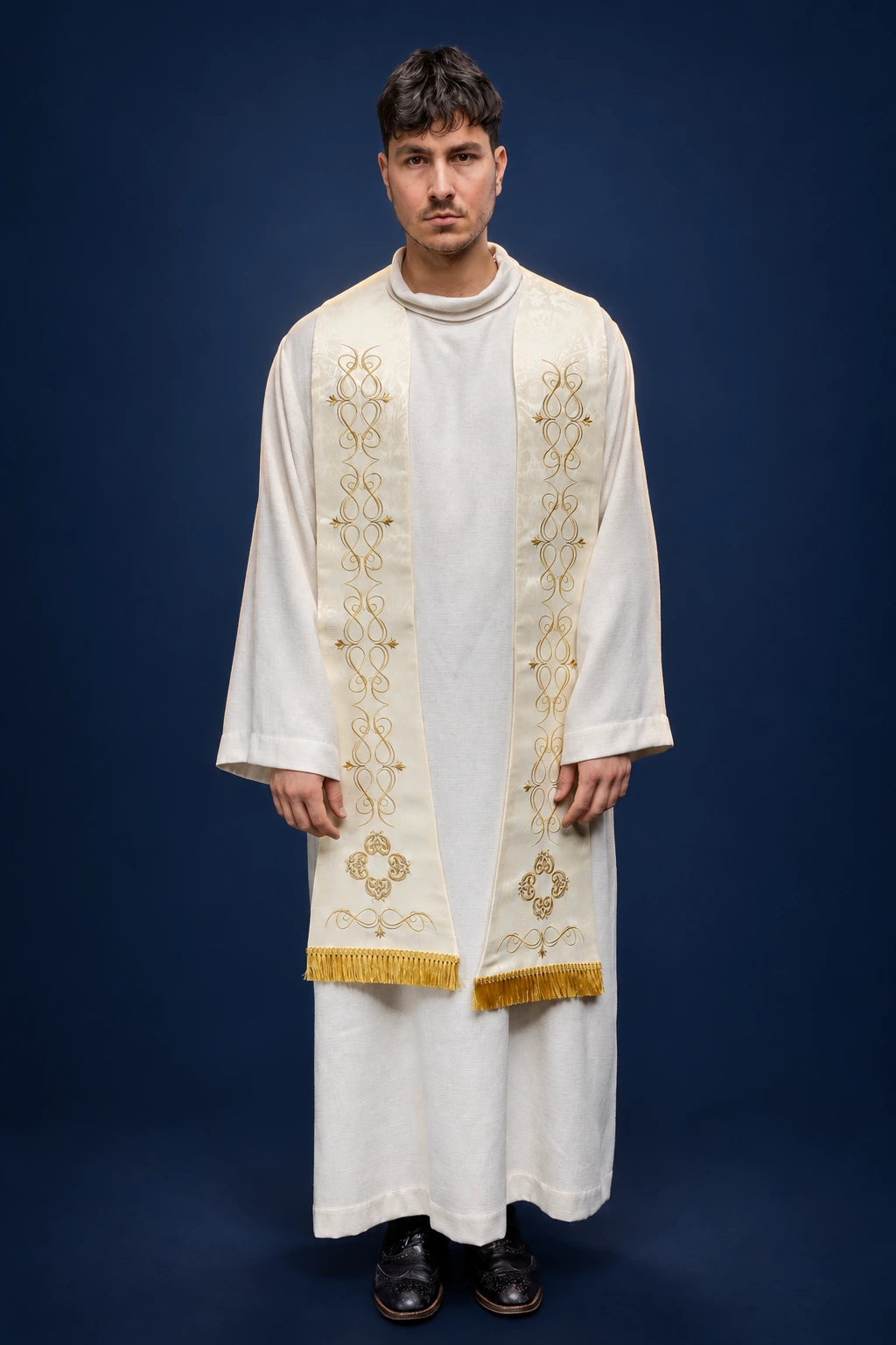 Front view of a Roman stole with gold embroidered vertical motifs and fringe, worn over a white alb.