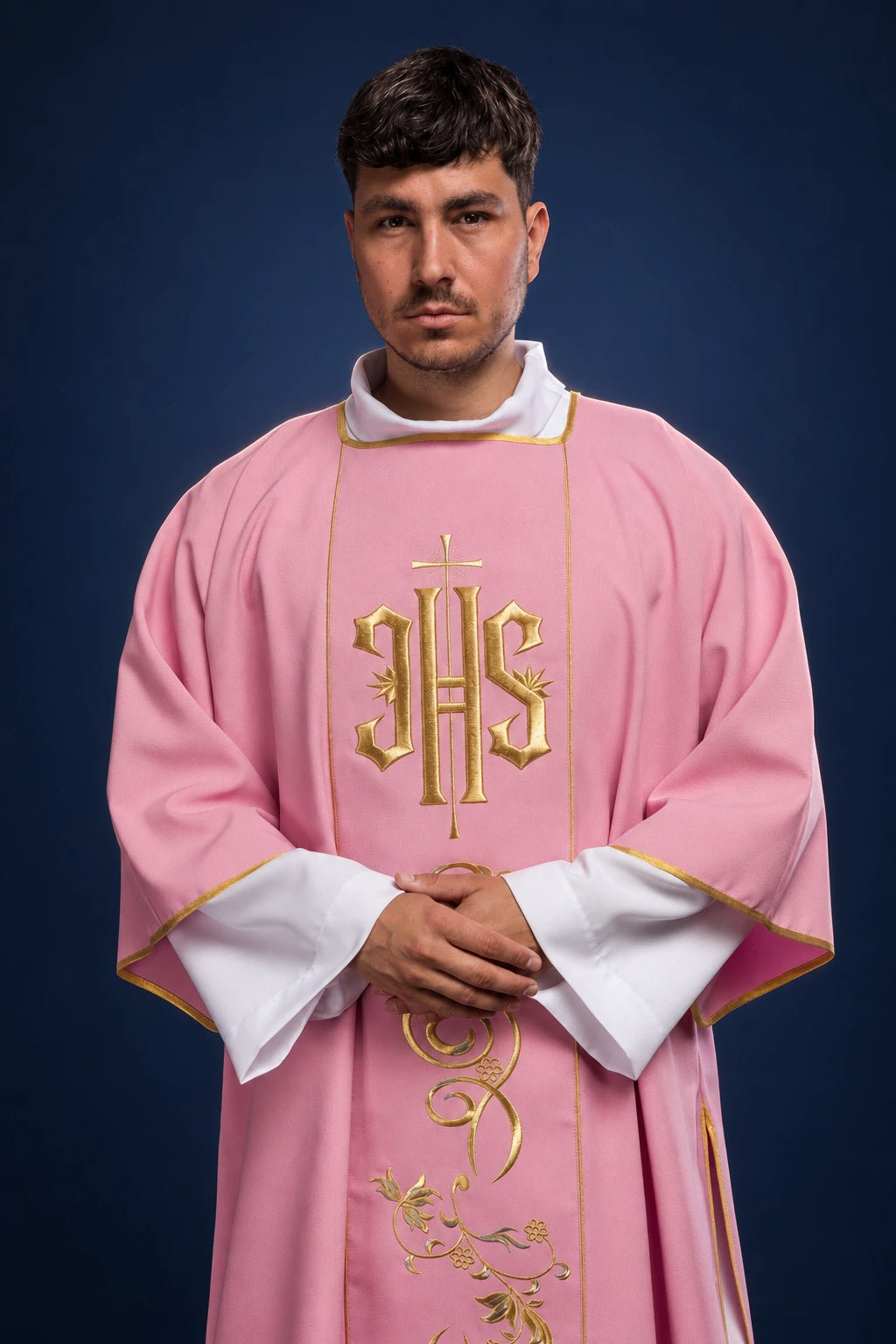 Front view of a rose dalmatic with gold embroidered IHS orphrey and vine motif, worn over white sleeves