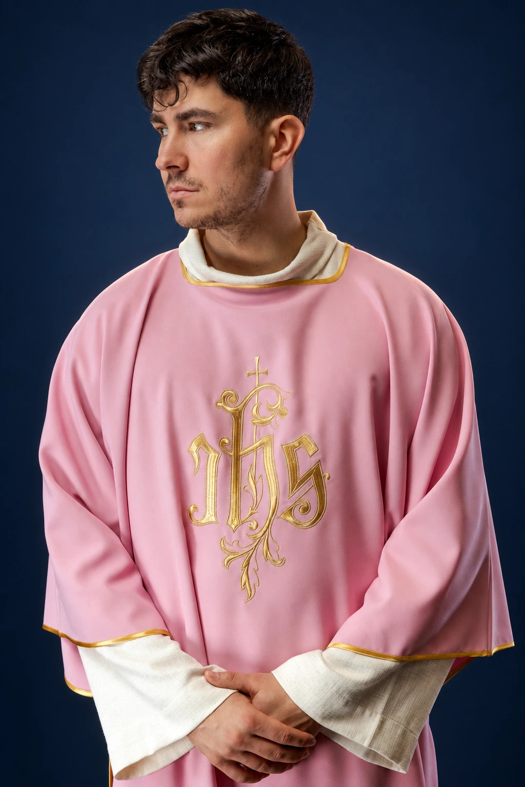 Front view of a rose dalmatic with gold IHS embroidery and gold trim at the sleeves and collar