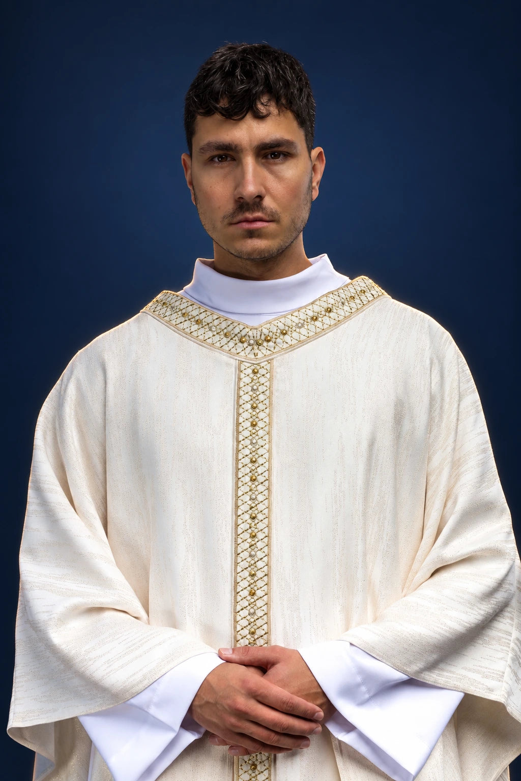 Front view of white chasuble with embroidered gold orphrey and collar, over a white alb collar.