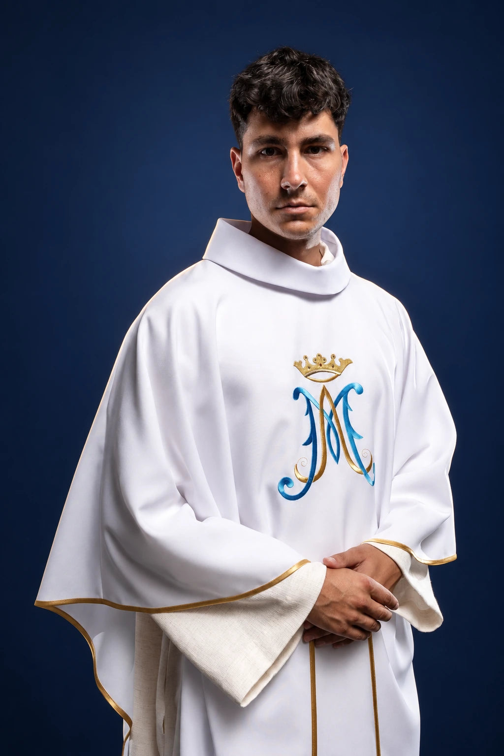 Front view of a white chasuble with gold trim and embroidered Marian monogram on the chest