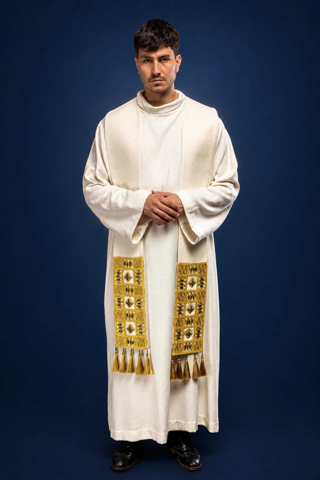 Front view of a white priest’s stole with gold stone trim and fringe, worn over a long alb