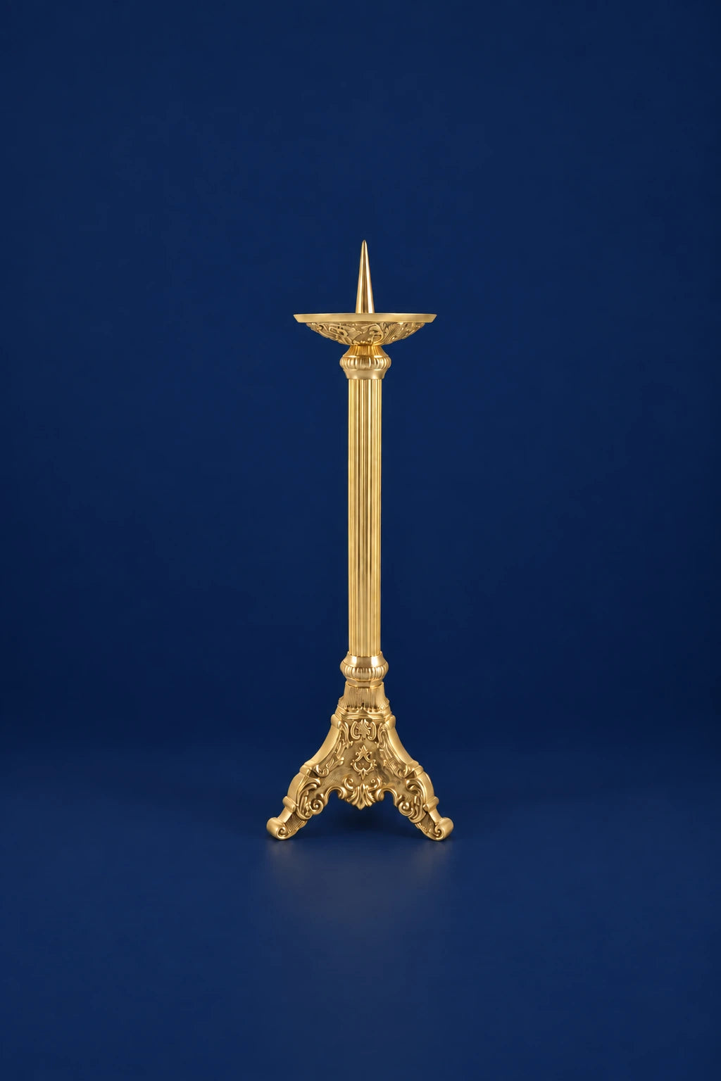 Full view of a gold-finish brass candlestick with ornate tripod base and slender column