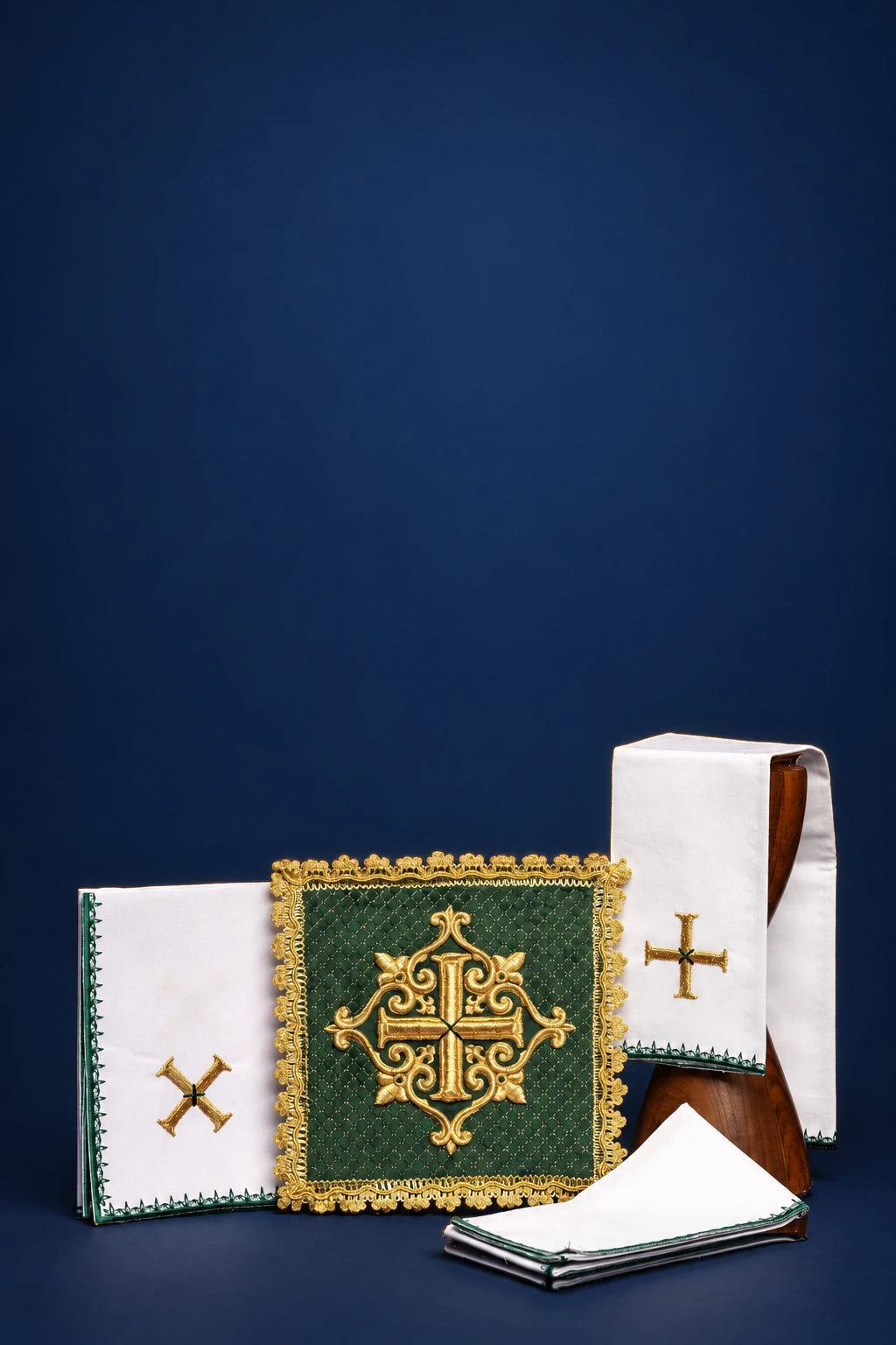 Green velvet altar linen set with gold embroidered cross and decorative trim, shown folded and stacked