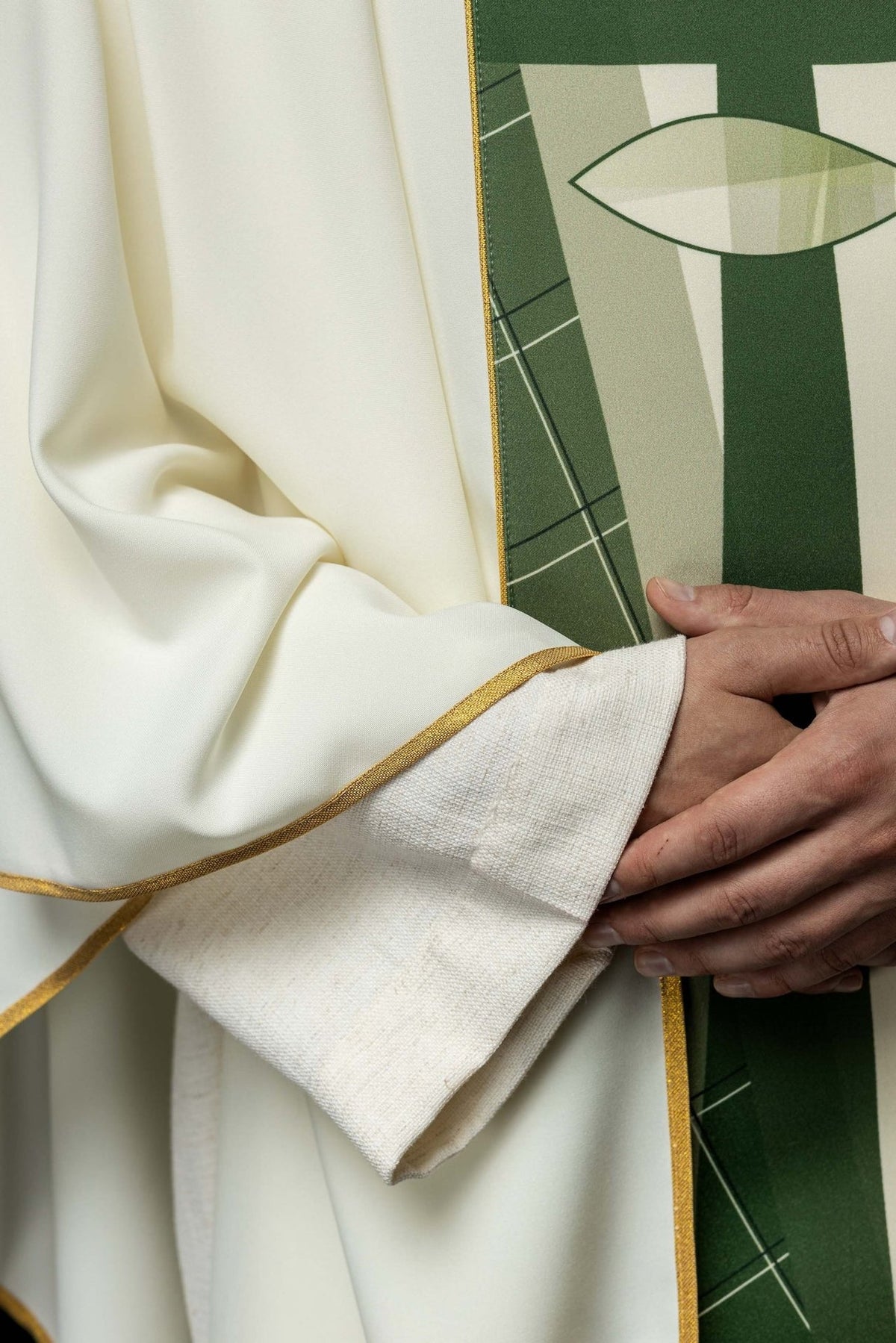 White chasuble close-up showing green geometric embroidery and gold trim