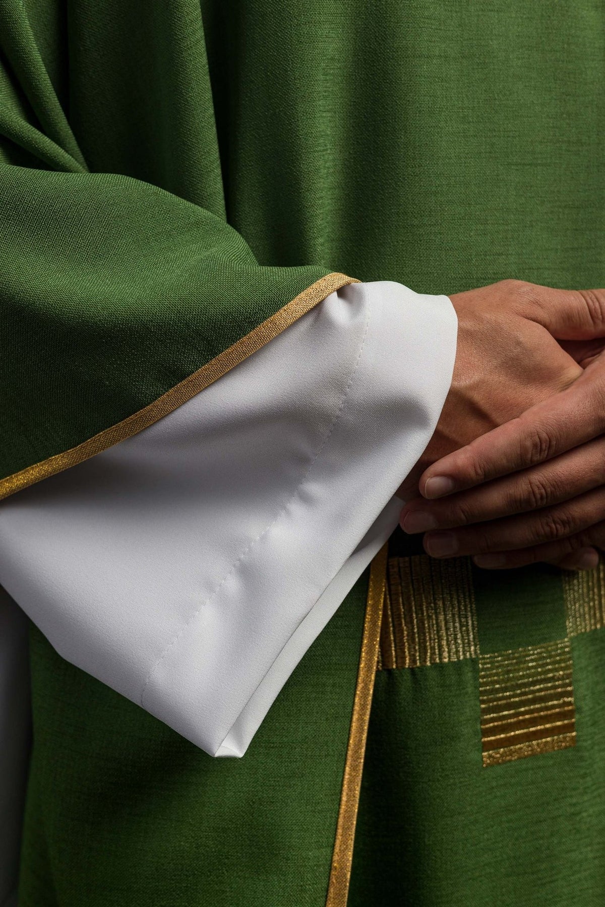 Green chasuble close-up showing gold trim at the sleeve edge