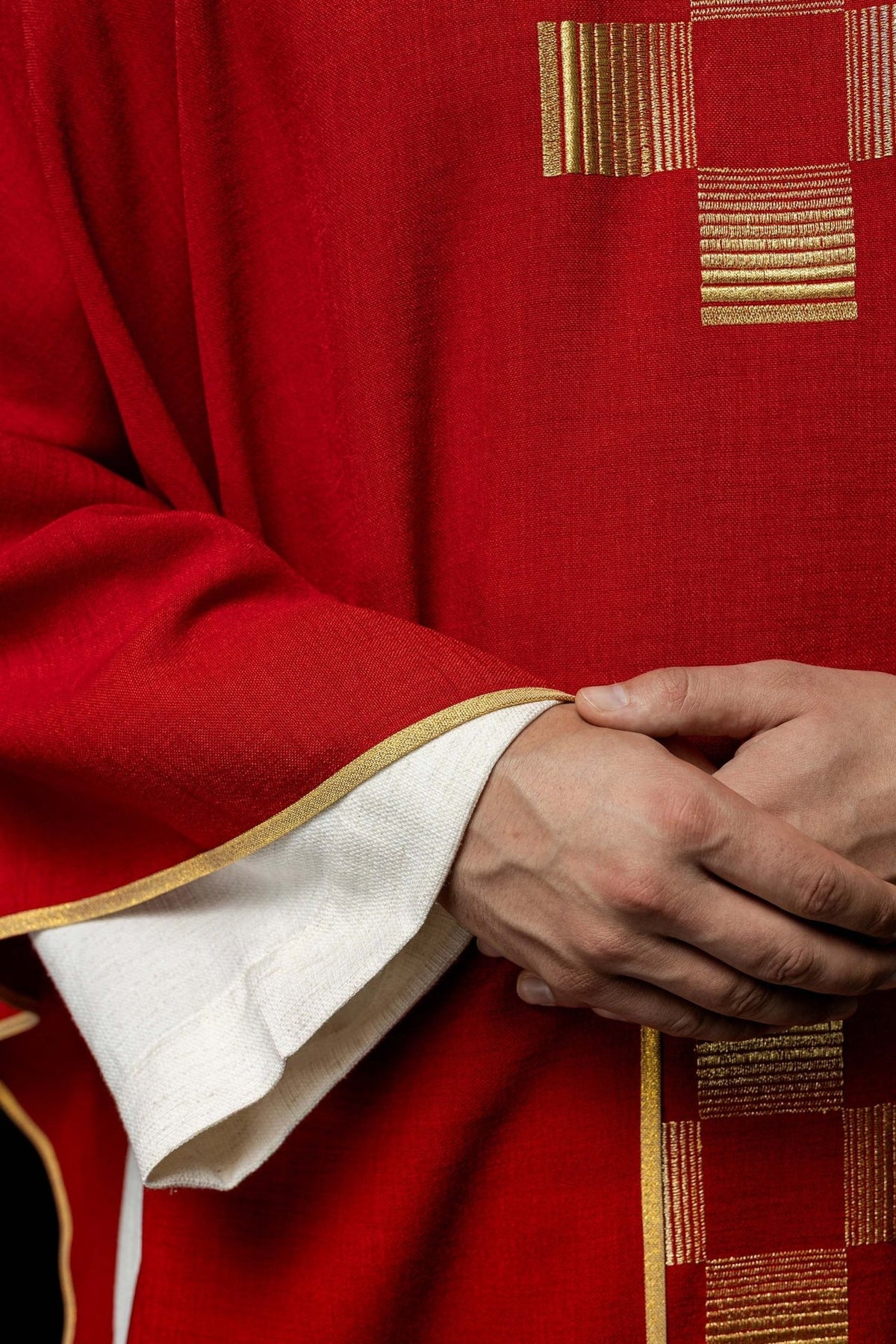 Red chasuble detail showing gold trim and white sleeve lining