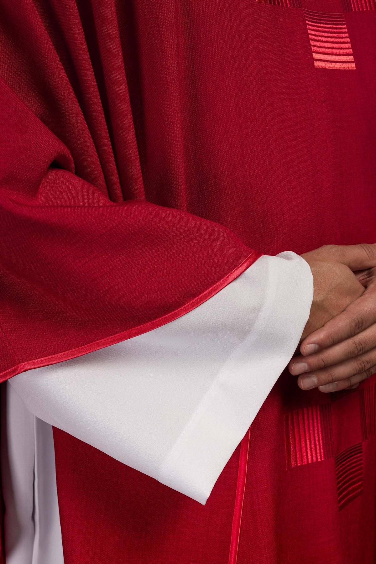 Red chasuble close-up showing red satin trim and embroidered cross
