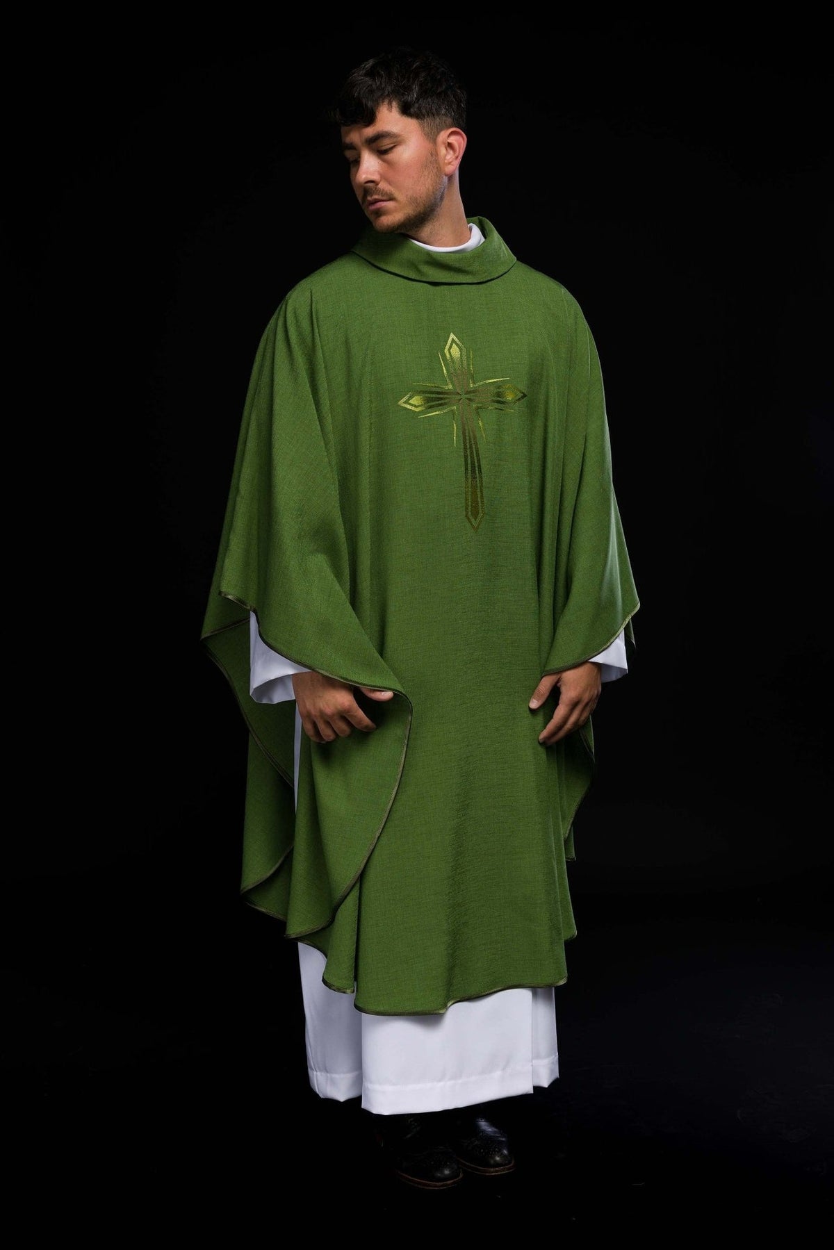 Green chasuble worn from the front at an angle, showing the cross and flowing trim