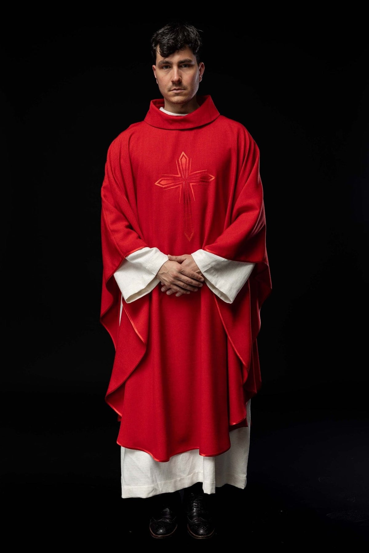 Red chasuble back view showing the embroidered cross and flowing trim