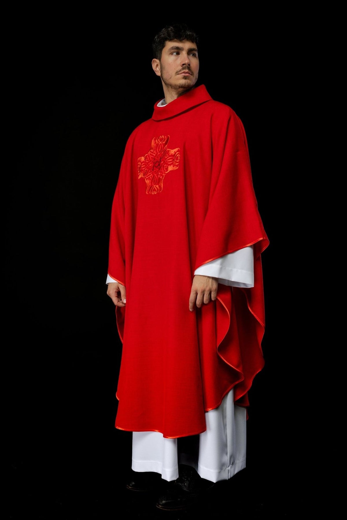 Red chasuble three-quarter view showing cross embroidery and satin trim