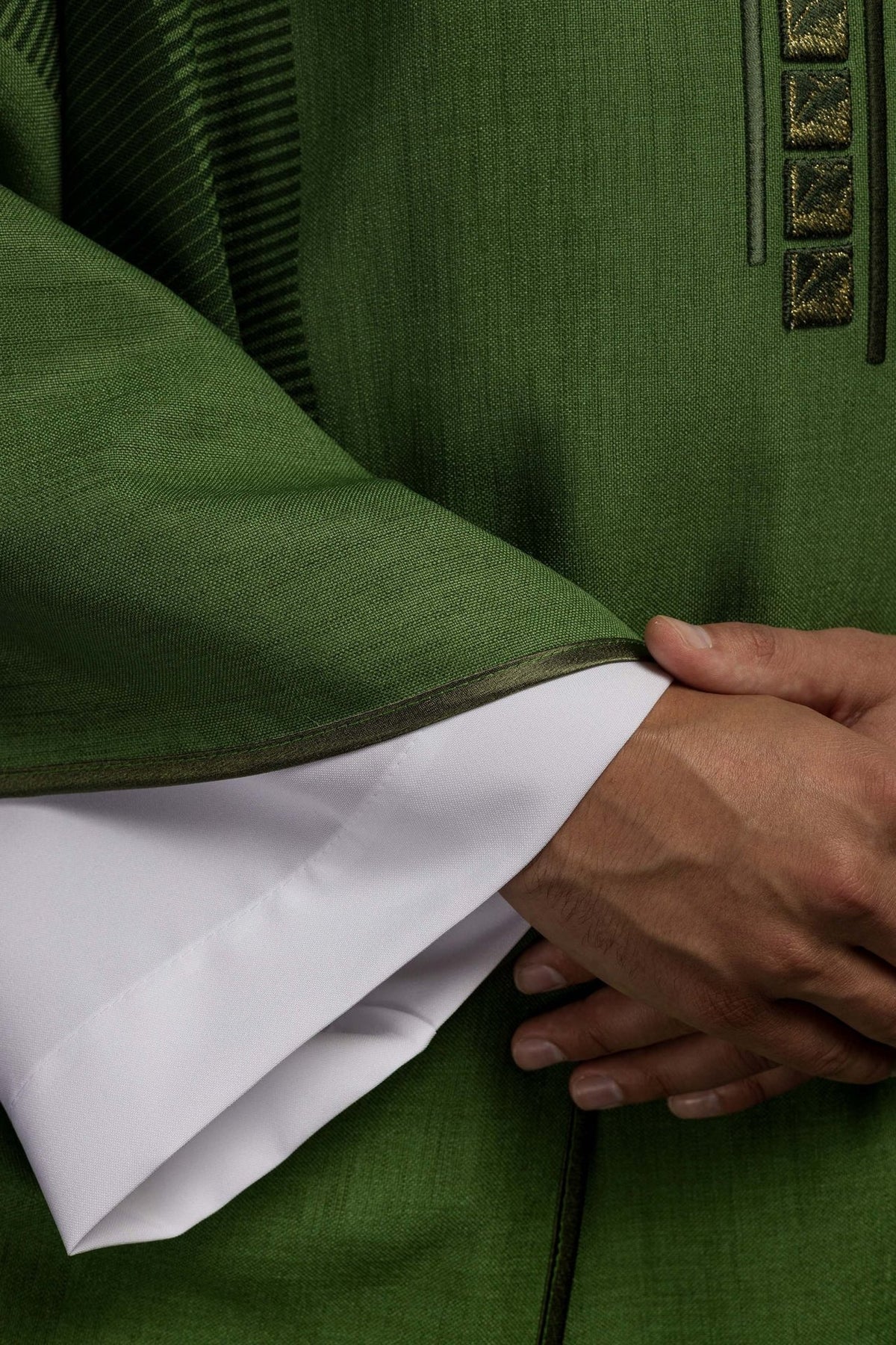 Green chasuble close-up showing woven fabric and dark trim