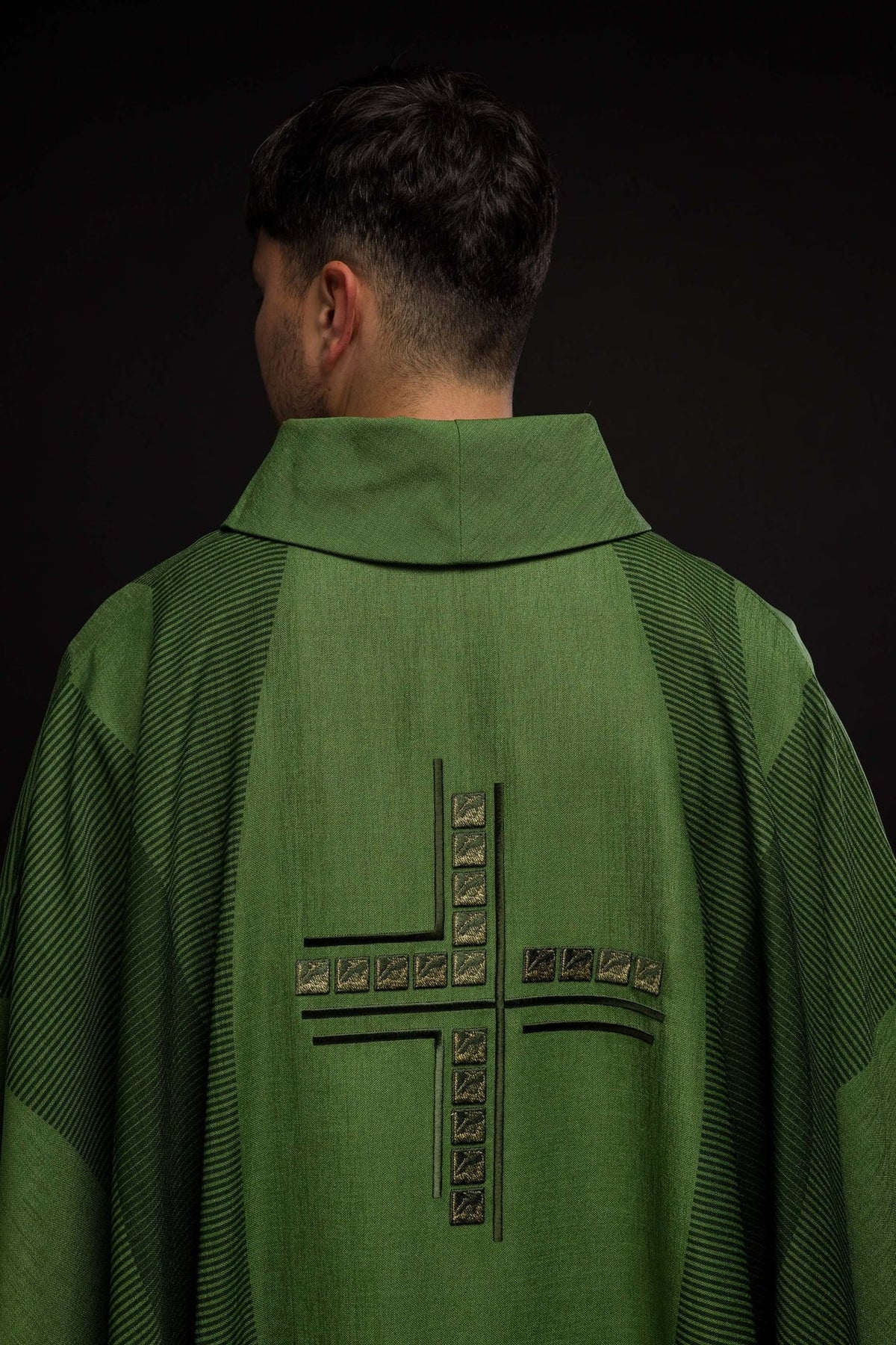 Green chasuble sleeve detail with dark trim and striped fabric panels