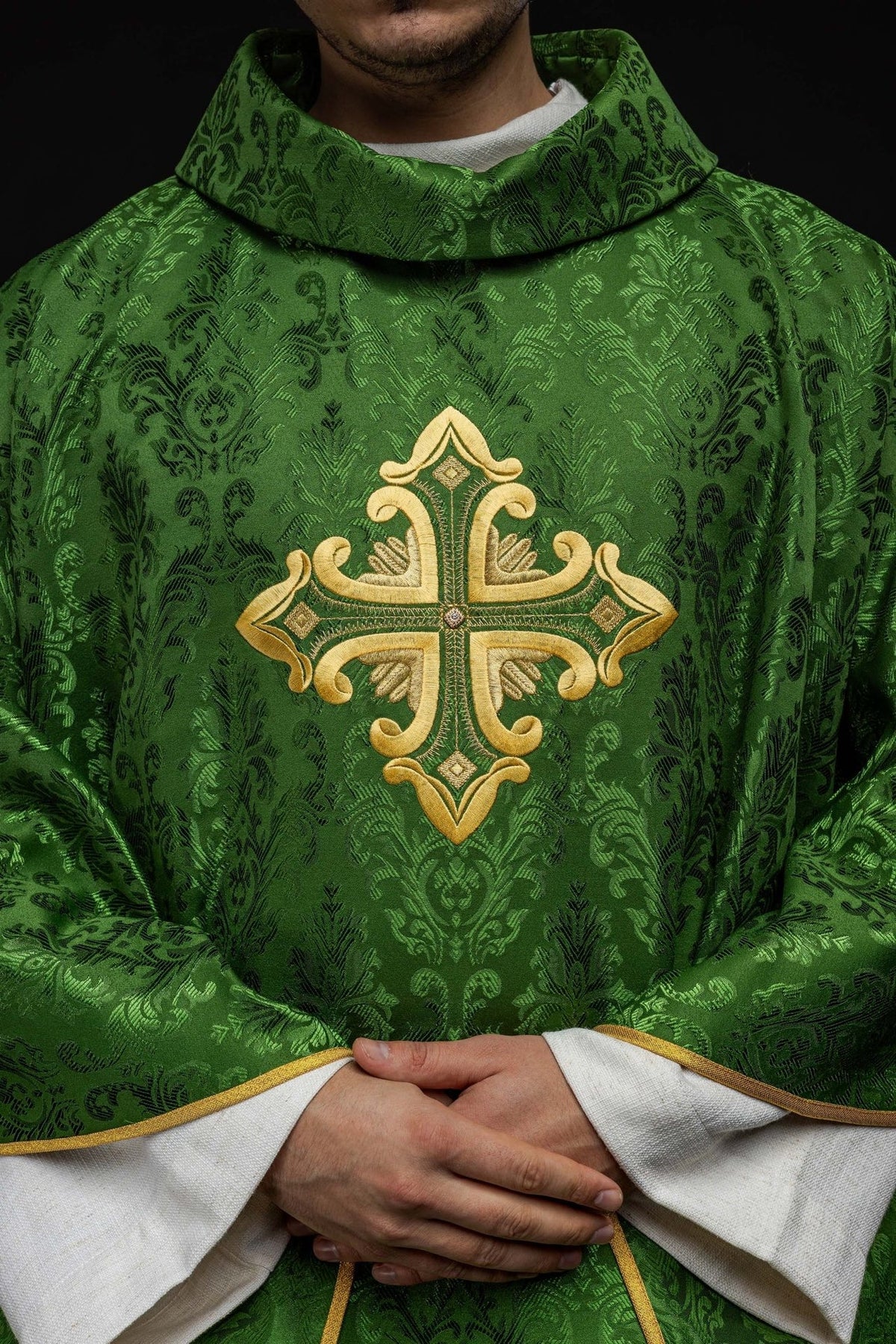 Green chasuble front close-up showing gold embroidered cross and satin pattern