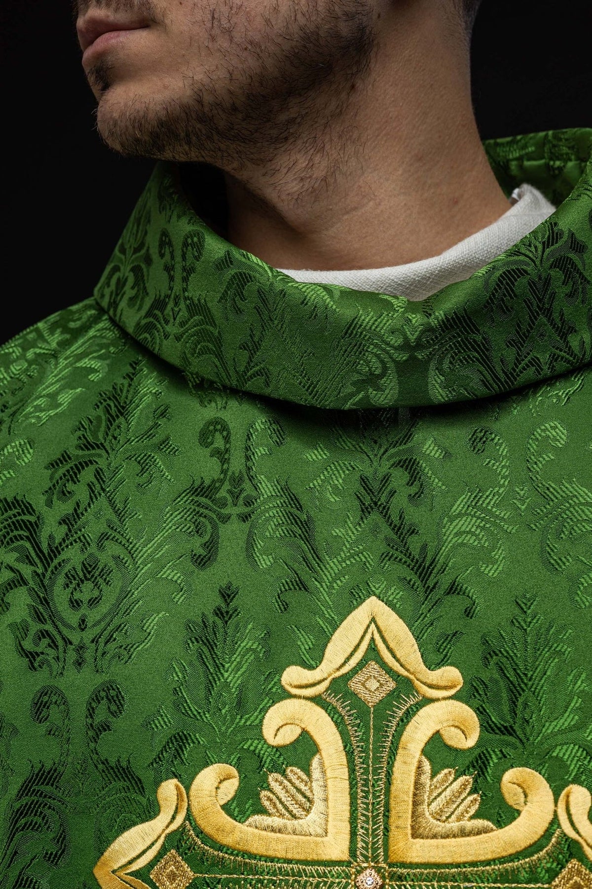 Green chasuble side close-up with patterned satin and gold trim