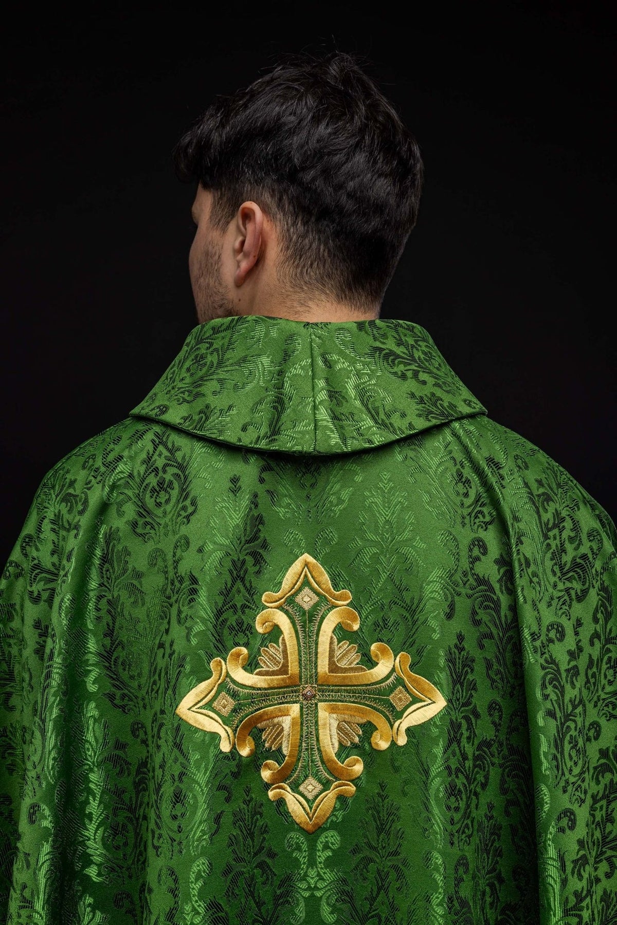 Green chasuble gold embroidered cross close-up on patterned satin