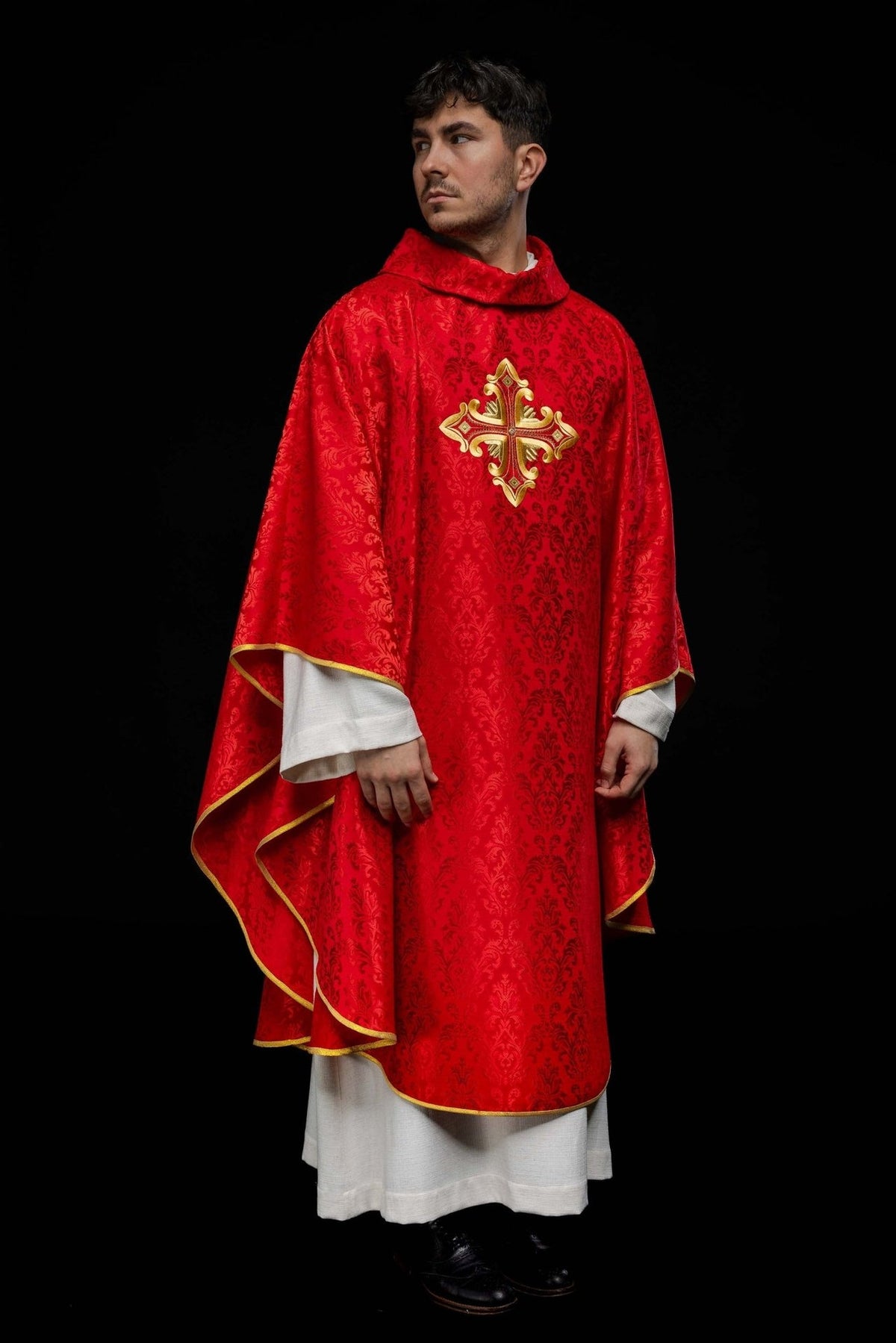 Red chasuble, three-quarter view showing patterned fabric, gold cross embroidery and trim