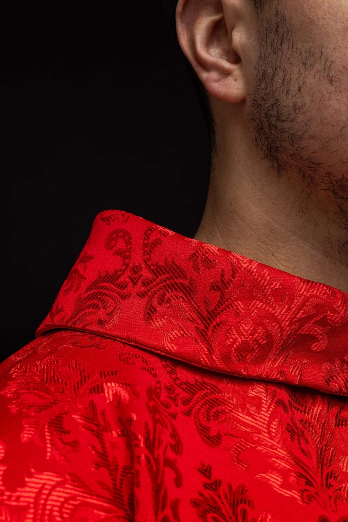 Red chasuble close-up showing patterned fabric and gold trim at the edge