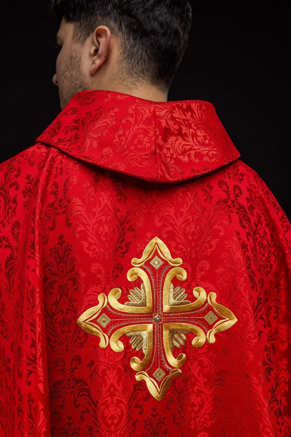 Red chasuble back close-up with patterned fabric and gold cross embroidery
