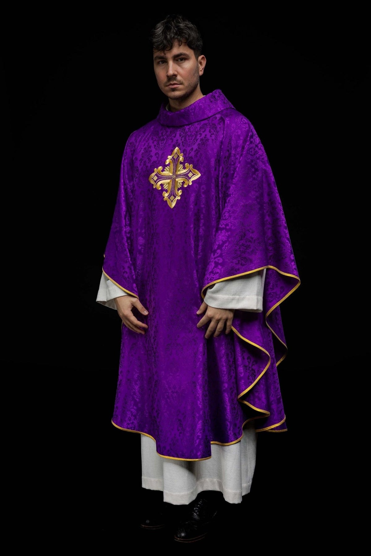 Purple chasuble worn full length, showing gold cross embroidery and trim