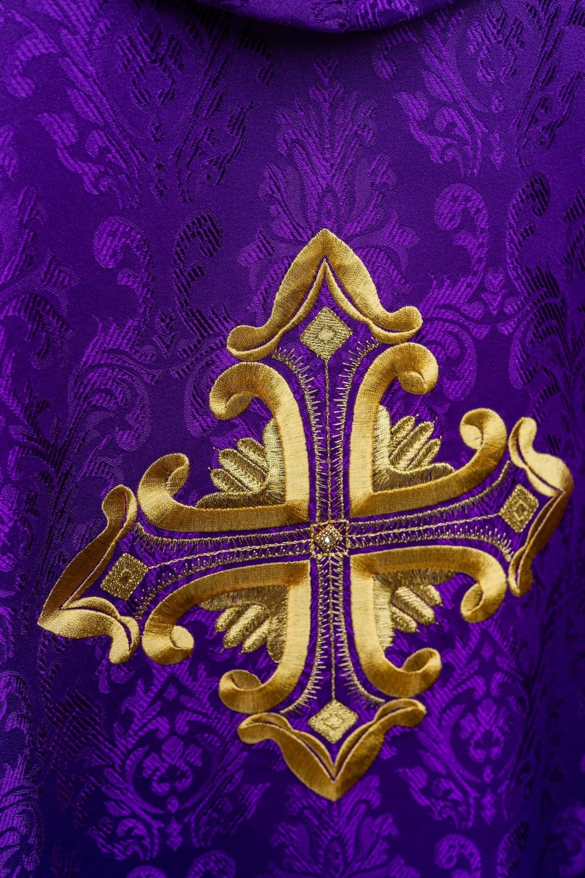 Purple chasuble gold cross embroidery close-up on patterned fabric
