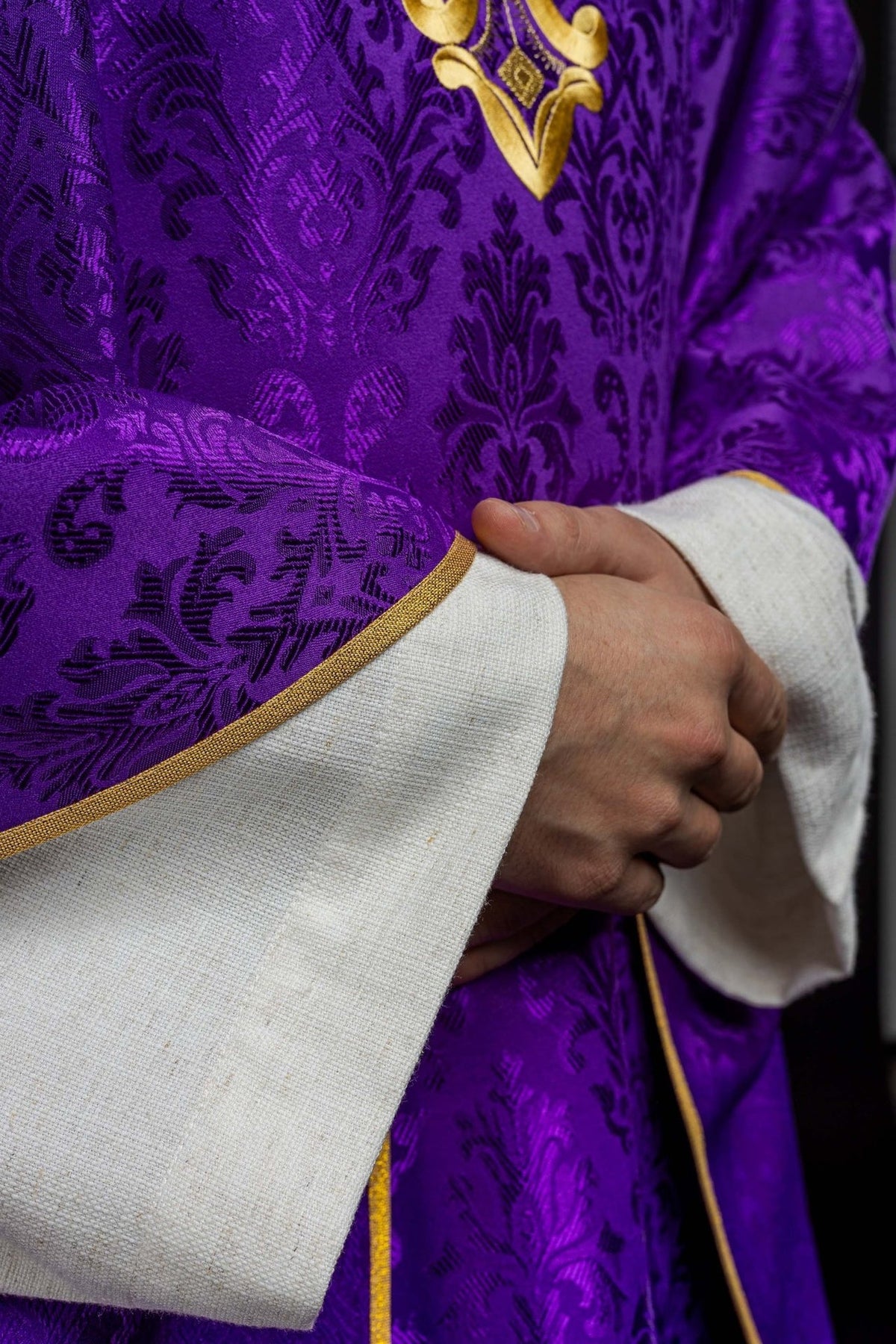 Purple chasuble patterned fabric and gold trim close-up
