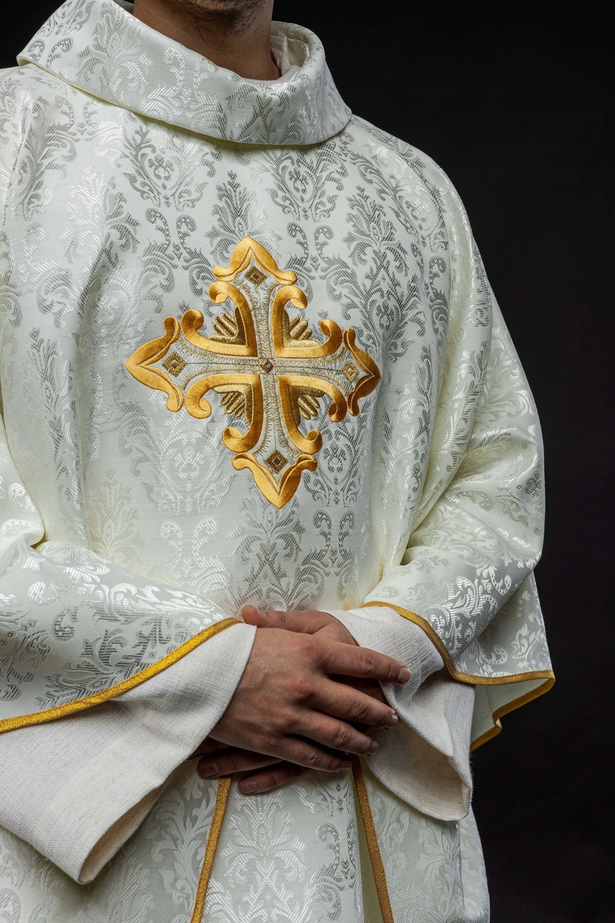 Ecru chasuble front close-up showing stand-up collar, patterned fabric and gold cross embroidery